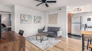Ein modernes Wohnzimmer mit grauem Sofa, einem Holztisch und einem Deckenventilator.