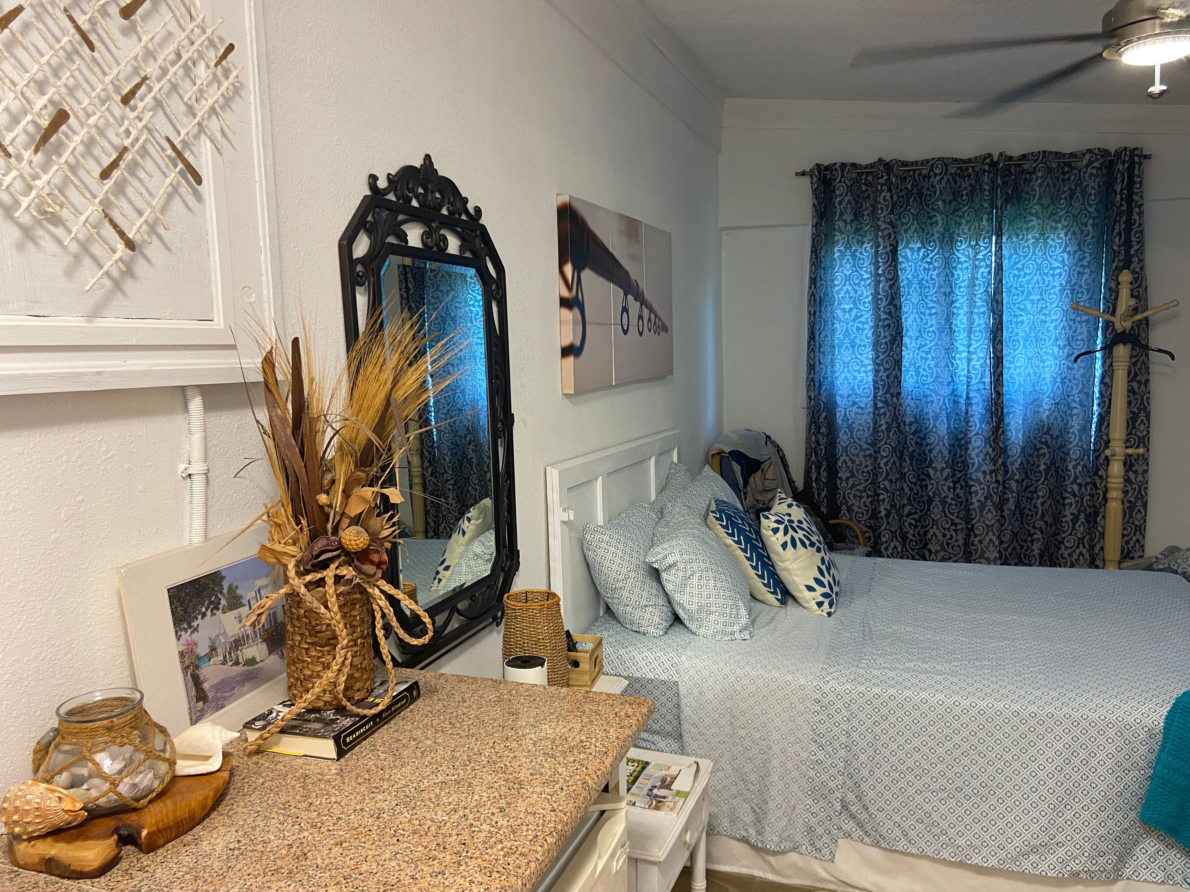 Un dormitorio con cama, cómoda, espejo y ventana con cortinas.