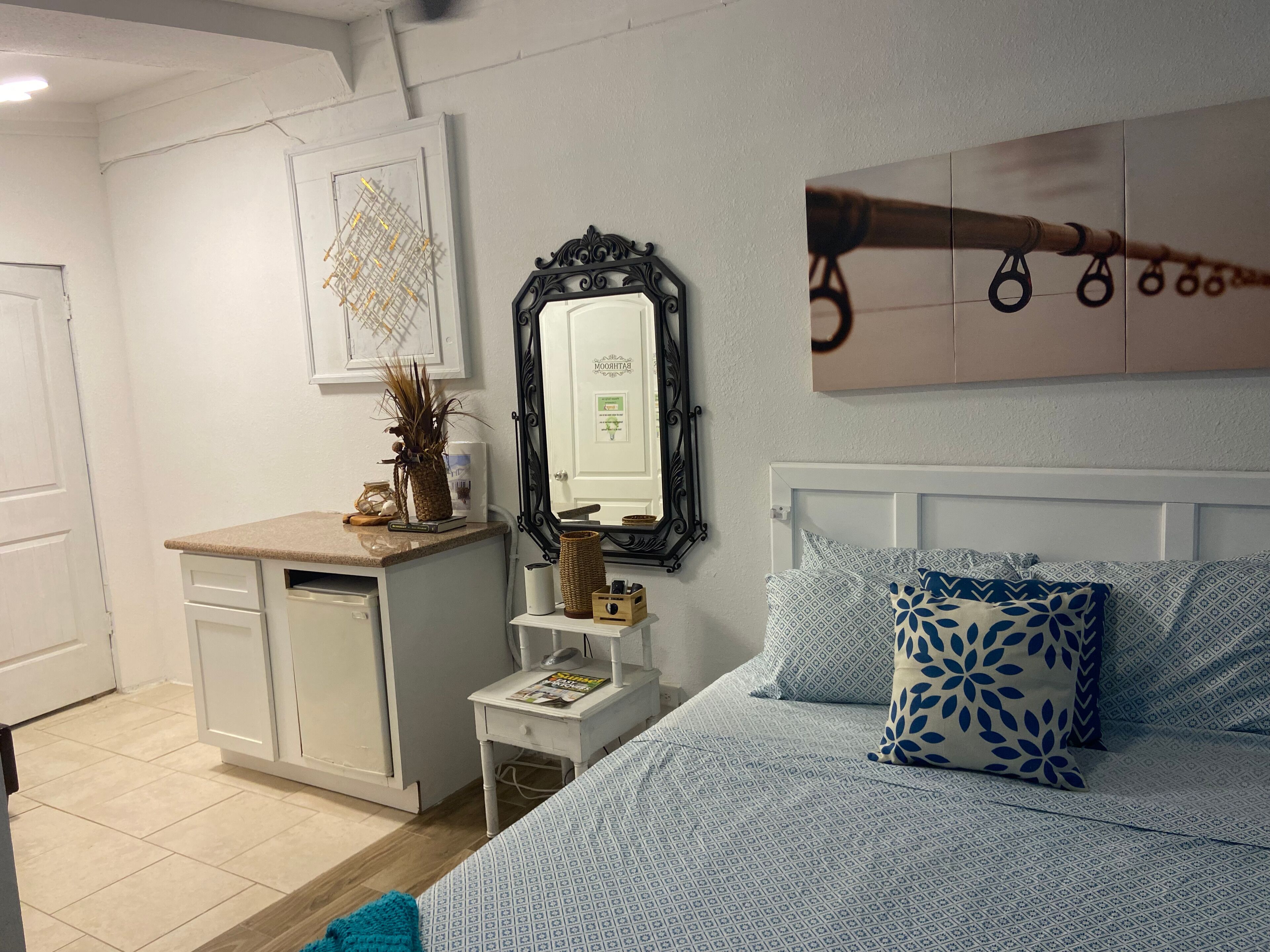 A bedroom with a bed, a dresser, a mirror, and a wall-mounted artwork.