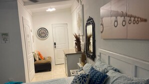 A bedroom with a bed, a nightstand, a dresser, a mirror, and a door leading to another room. - Rosebud (Rock Sound)