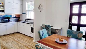 A modern kitchen with white cabinets, a wooden countertop, and a ceiling fan. - Beach pad with a modern touch  in the heart of Iluka (Iluka)