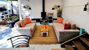 A covered patio area with wicker furniture, a central table, and a black stove. - Beach pad with a modern touch  in the heart of Iluka (Iluka)