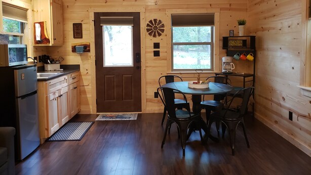 A wooden cabin interior with a kitchen, dining area, and a star decoration on the ceiling. - The Redbud Cabin at Roman Nose (Watonga)