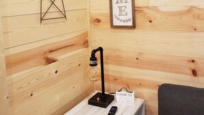 A wooden interior with a windmill, a 'WELCOME' sign, a table with a lamp, a remote control, and a 'COME IN' sign. - The Redbud Cabin at Roman Nose (Watonga)