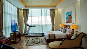A hotel room with a bed, a treadmill, a TV, and a large window with curtains. - Galaxy La Palm Royal Hotel (Port Harcourt)