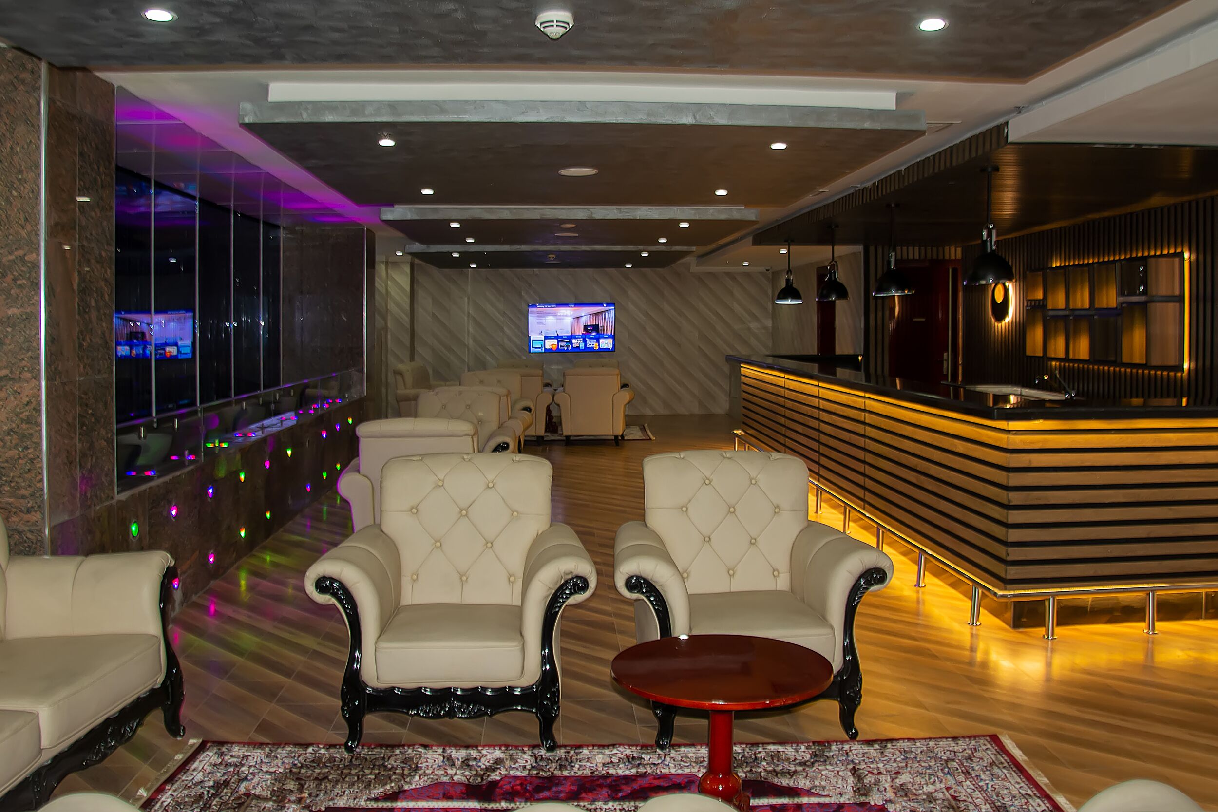 Una hall con un'area bar, posti a sedere e uno schermo televisivo.