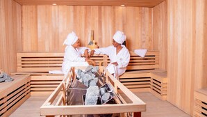 A wooden sauna with benches and a stone heating system. - Galaxy La Palm Royal Hotel (Port Harcourt)