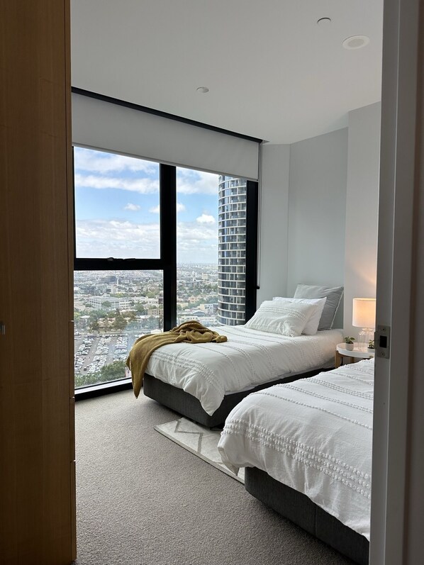 Enjoy a panoramic city view from the large window in this stylish room with two comfortable beds and a bedside table.
