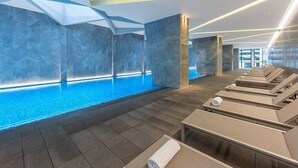 A modern spa area with a pool, lounge chairs, and a geometric ceiling design. - 3 bedroom apartment in the heart of the CBD. (Melbourne)