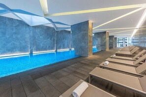 Relax in a serene pool area surrounded by lounge chairs and geometric patterns.