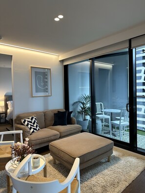Relax in this stylish living room with a sofa, armchair, and ottoman, plus a patio area with a table and chairs.