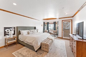Relax in this serene bedroom with a large bed, wooden headboard, and comfortable seating area.