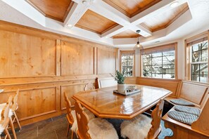 Enjoy meals in this dining area with a large table and comfortable chairs, surrounded by natural light and a view of the outdoors.