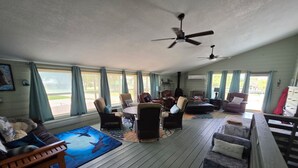 Un vaste espace de vie doté d’une grande table ronde, de nombreux sièges et d’un ventilateur de plafond.