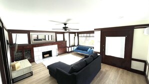 Una sala de estar con chimenea, un sofá, un sofá azul y un ventilador de techo.