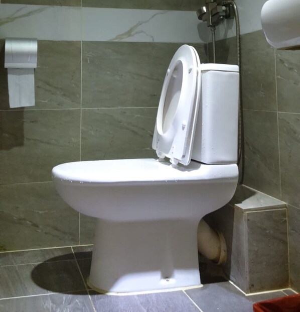 A toilet in a bathroom with a marble tile wall and a paper towel dispenser. - Kam Mun Guest House (Kowloon)