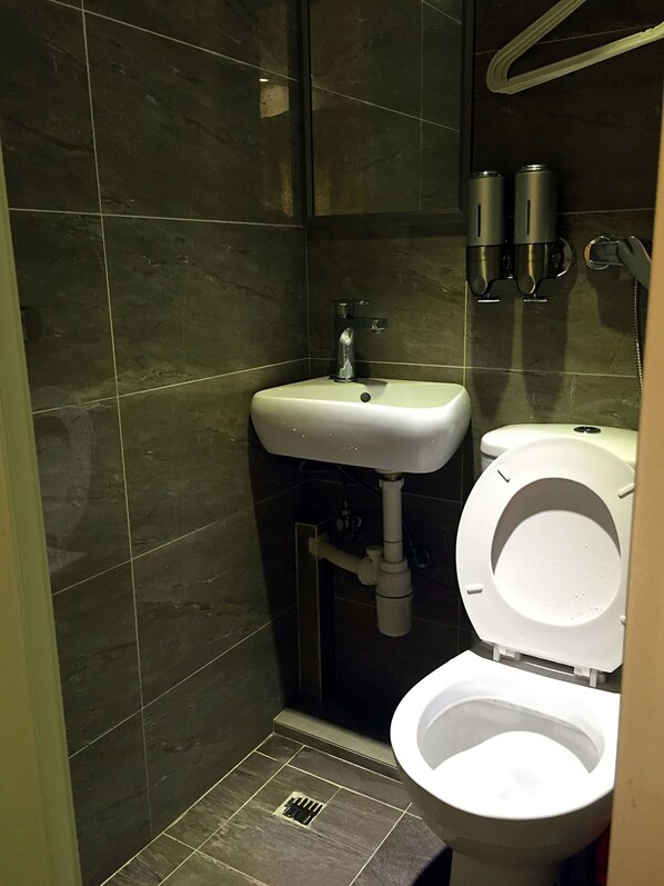 A small bathroom with a white sink, a toilet, and a shower area. - Kam Mun Guest House (Kowloon)