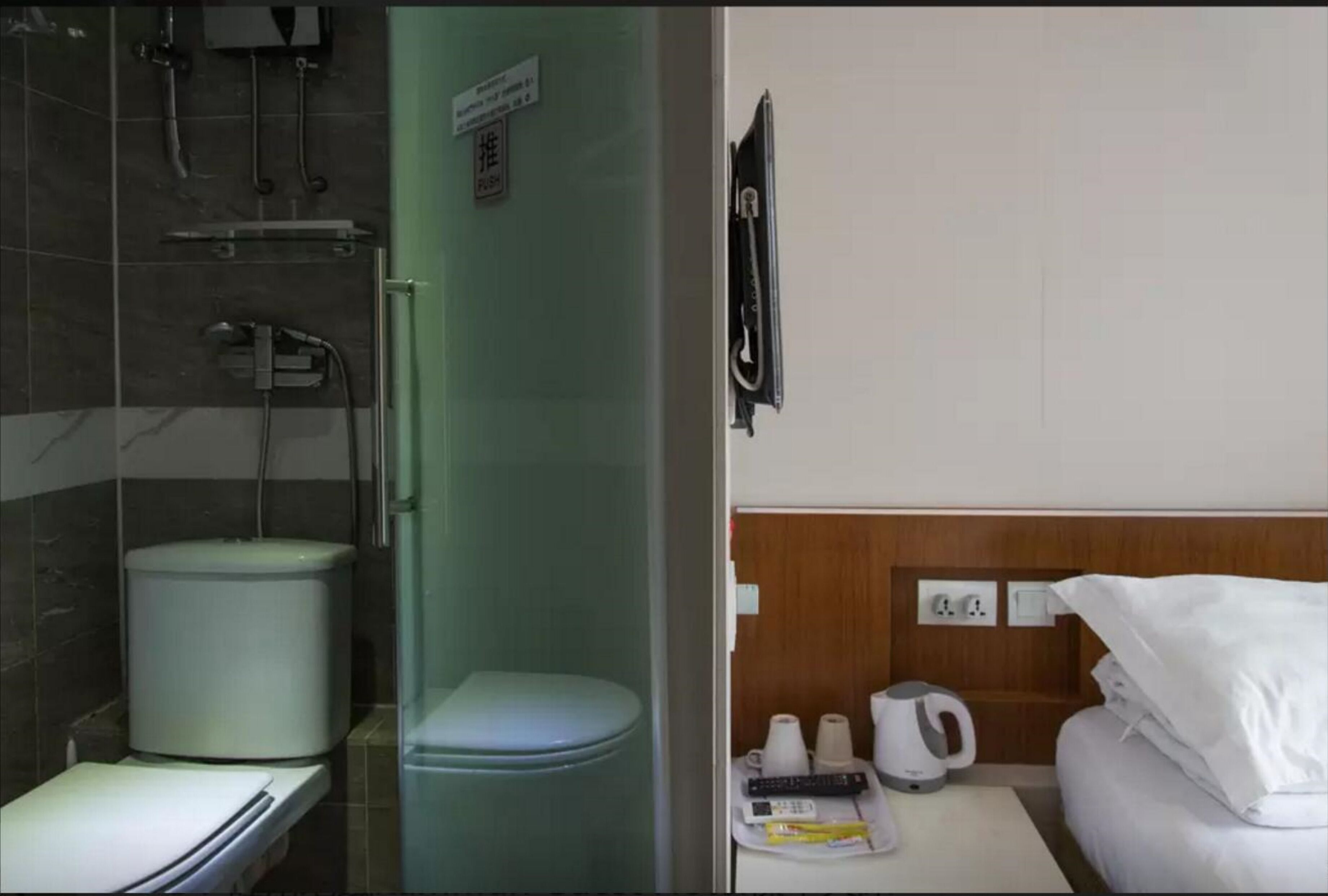Ein Badezimmer mit Toilette, Dusche und Waschbecken. An der Wand befindet sich ein Schild und ein Handtuchhalter.