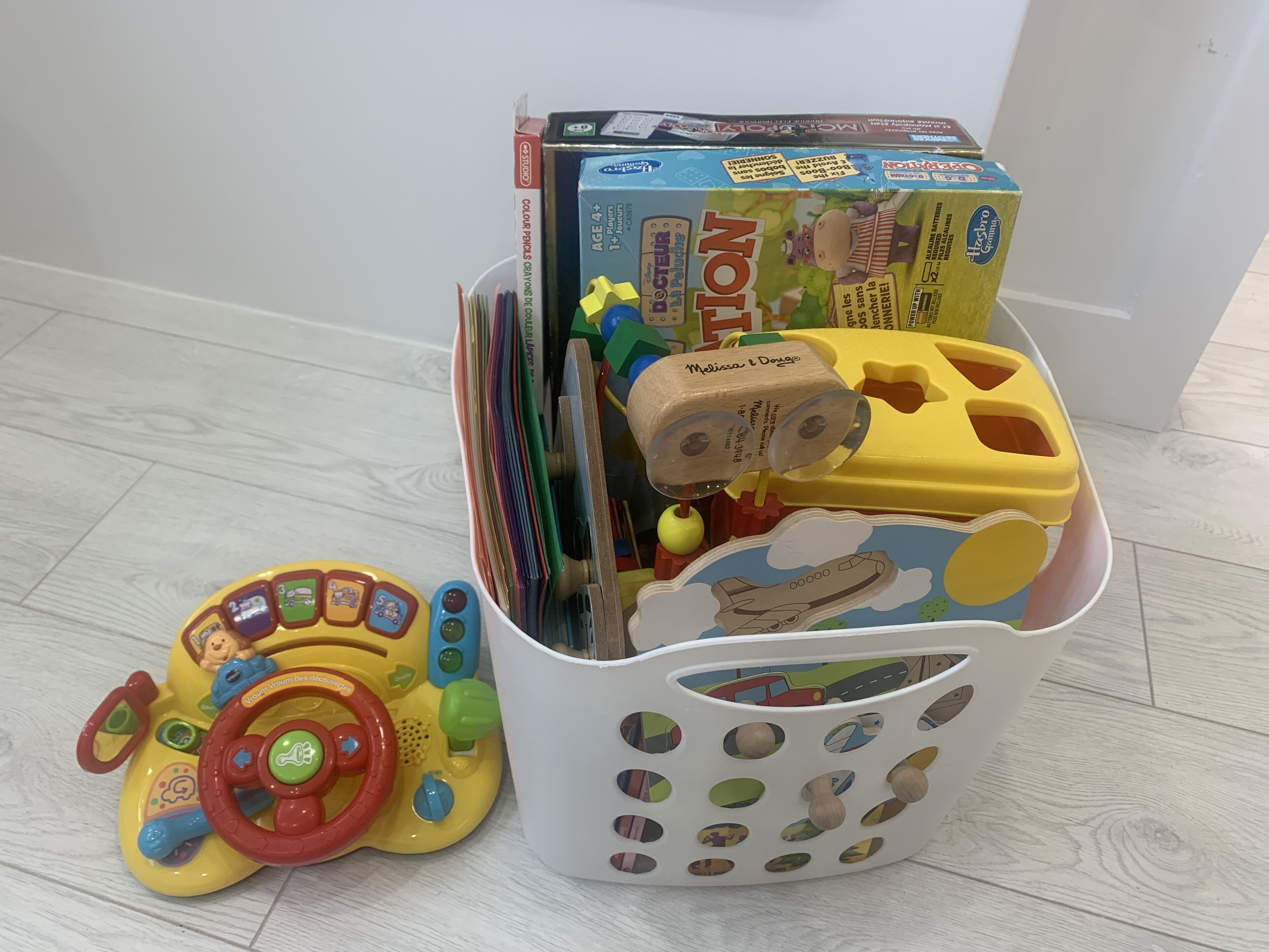 A storage basket filled with children's toys and books, including a toy car and a box labeled "Notion."