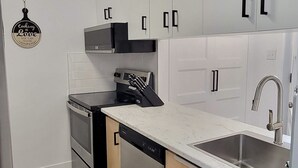 A modern kitchen with white cabinets, a stainless steel sink, and a built-in oven. - MONTSKI | Luxurious 〽️ condo (Beaupré)