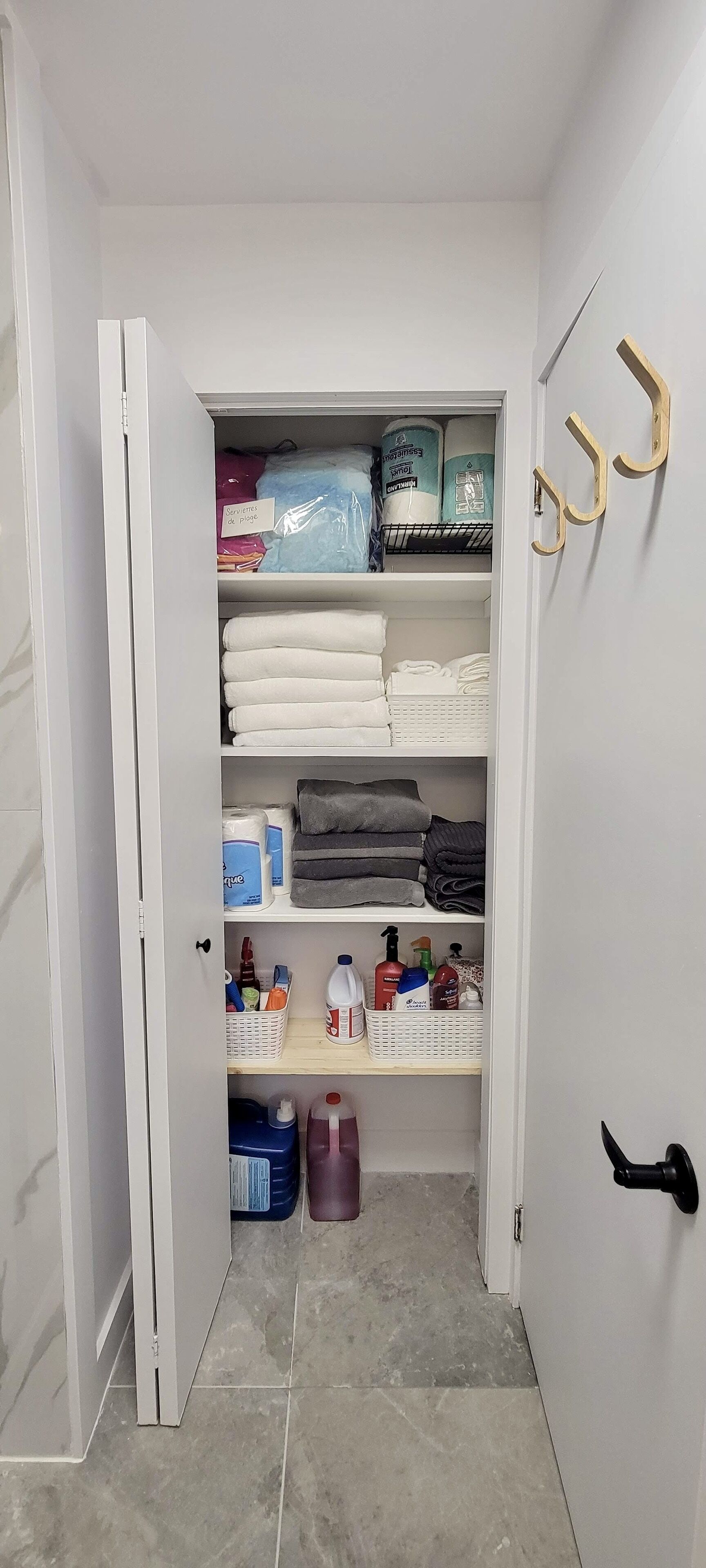 A walk-in closet with shelves containing folded towels, toiletries, and cleaning supplies.