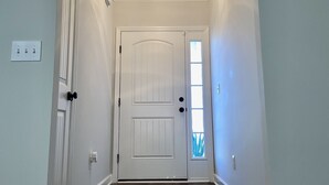 A hallway with a white door, a ceiling light, and a small window. - Modern Ranch-Style Retreat — Prime location for the Course ⛳️ (Augusta)