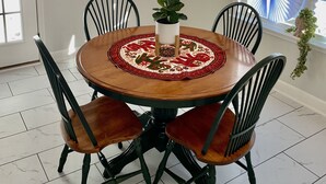 A dining area with a round wooden table, black chairs with brown cushions, a decorative table runner, a potted plant, and a chandelier. - Modern Ranch-Style Retreat — Prime location for the Course ⛳️ (Augusta)
