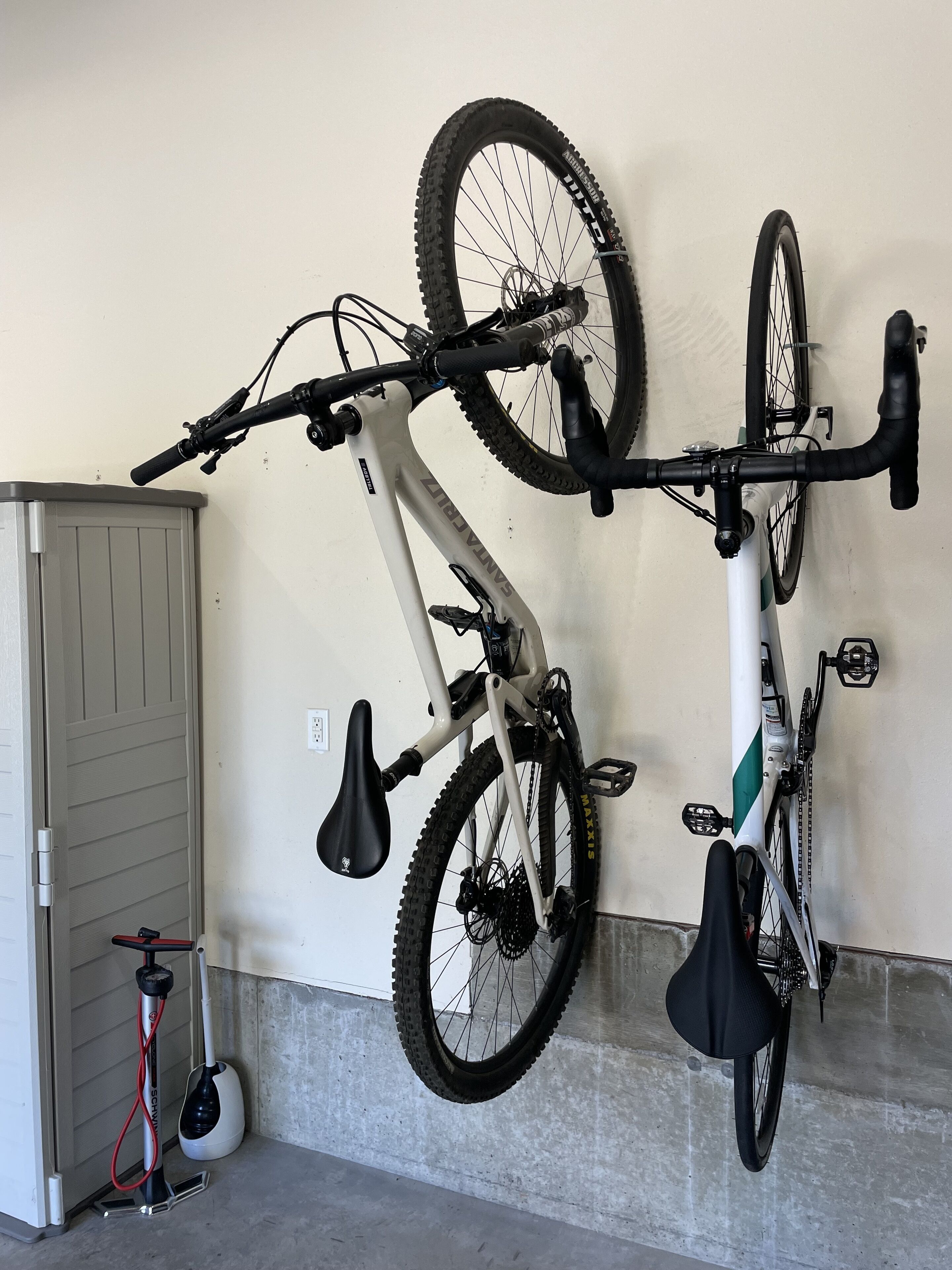 A bicycle mounted on a wall, a mop and broom, and a door.