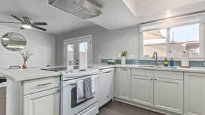 Una cocina moderna con armarios blancos, horno empotrado, placa de cocina y ventana con vistas.