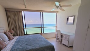 Un dormitorio con cama, escritorio, silla y vistas al océano.