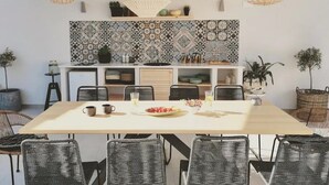 Una cuina moderna amb una illa gran, llums penjants de vímet i un respatller amb un disseny decoratiu.