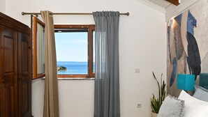 Un dormitori amb un llit, una finestra amb cortines, una làmpada i una pintura penjada a la paret.