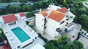 Un edificio de varios pisos con piscina en la azotea y zona de estar al aire libre.