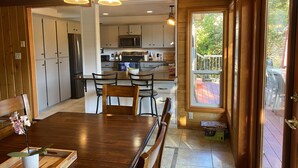 Una cocina moderna con armarios de madera, una isla central y un comedor con mesa y sillas de madera.