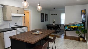 Une cuisine moderne dotée d’un îlot central, de meubles en bois et de luminaires suspendus.