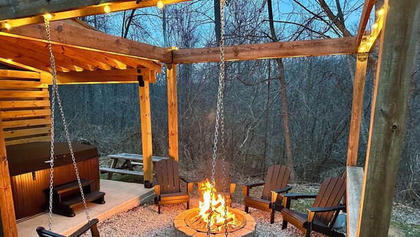 Un belvédère en bois doté d’un foyer, de sièges et d’une balançoire.