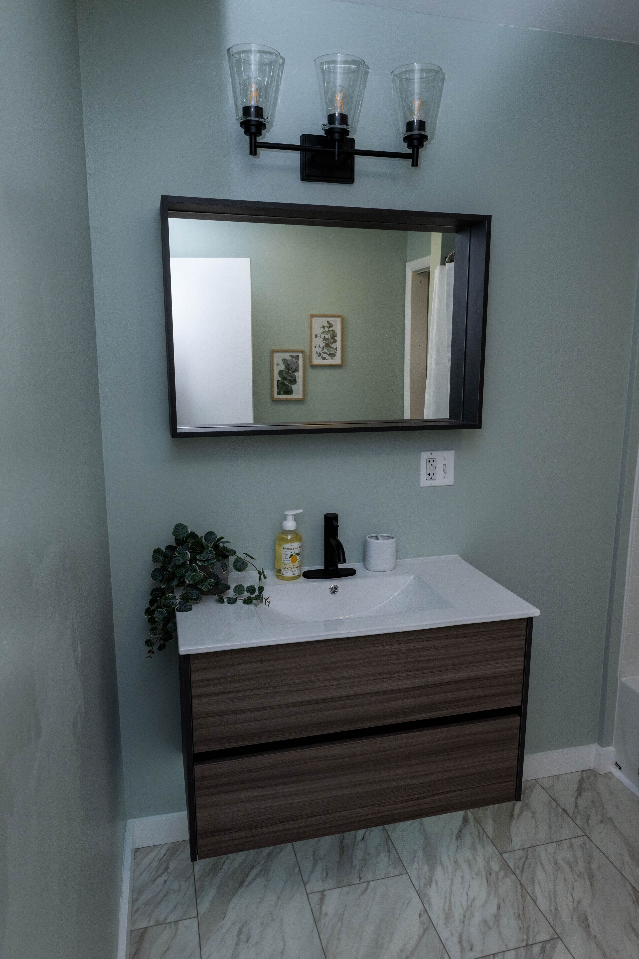 A bathroom with a white sink, dark wooden vanity, and a mirror above.