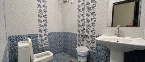 A bathroom with a toilet, bidet, sink, and a showerhead.