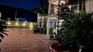 A two-story building with a paved driveway and a parked scooter. - PUSHKAR REGENCY RESORT (Pushkar)
