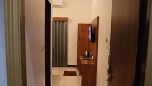 A hallway leading to a room with a wooden desk, a television, and a small cabinet. - PUSHKAR REGENCY RESORT (Pushkar)