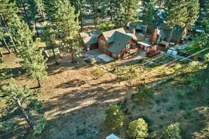 Traditional home surrounded by a well-maintained lawn and trees, with a driveway and fenced area.