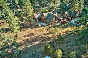 Traditional home surrounded by a well-maintained lawn and trees, with a driveway and fenced area.