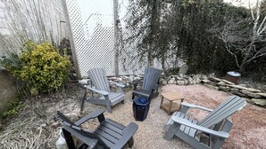 Un espace extérieur aménagé avec des fauteuils Adirondack, une petite table et une poubelle.