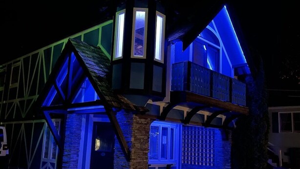 Un bâtiment traditionnel doté d’une tour imposante et de nombreuses fenêtres, illuminé par un éclairage bleu.