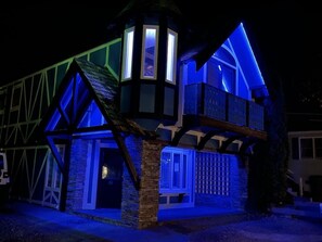 Un edifici tradicional amb una torre destacada i nombroses finestres, il·luminat amb llums blaves.