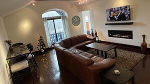 Un salon avec un canapé en cuir marron, une table basse et un téléviseur fixé au mur.
