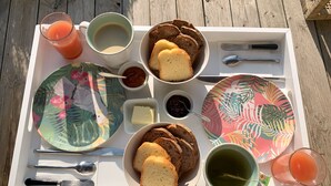Una bandeja con diversos alimentos, como pan, mantequilla, mermelada y una bebida.