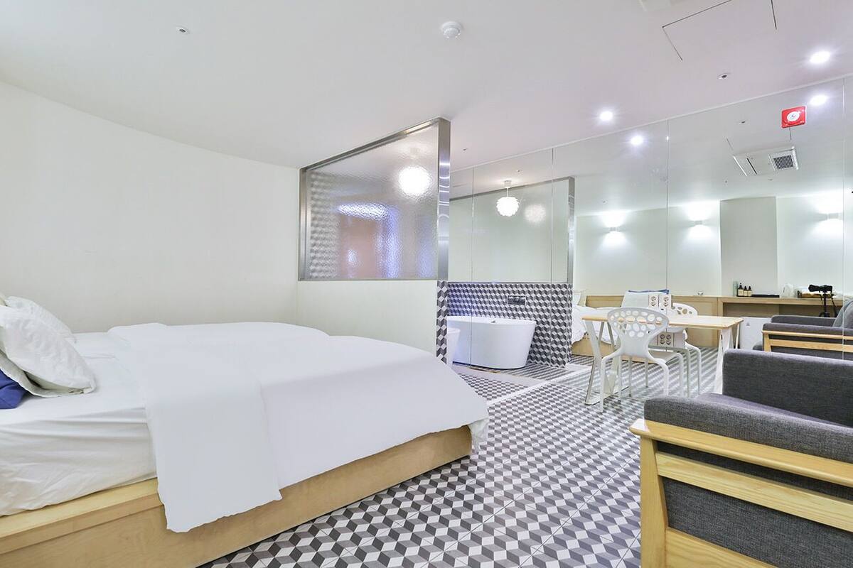 A hotel room with a bed, a desk, a chair, and a bathroom.