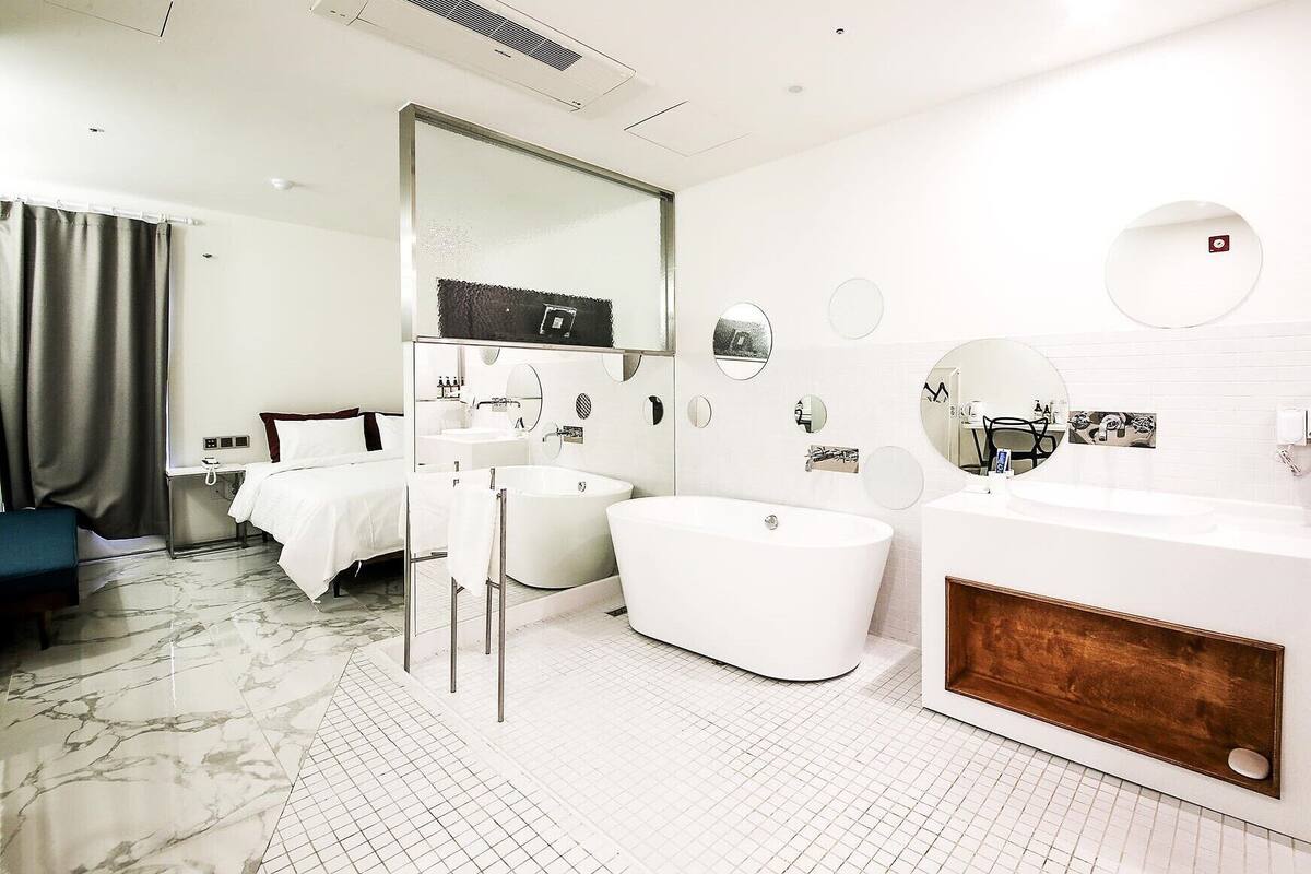 A modern hotel bathroom with a freestanding bathtub, a large mirror, and a vanity with a sink.