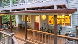 A covered porch with outdoor seating, a grill, and a view of the house interior.